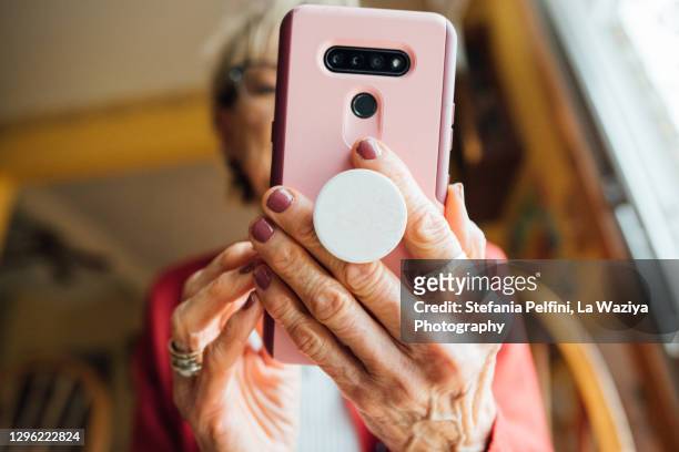 senior woman looking at her smartphone while at home. - phone cover stock pictures, royalty-free photos & images