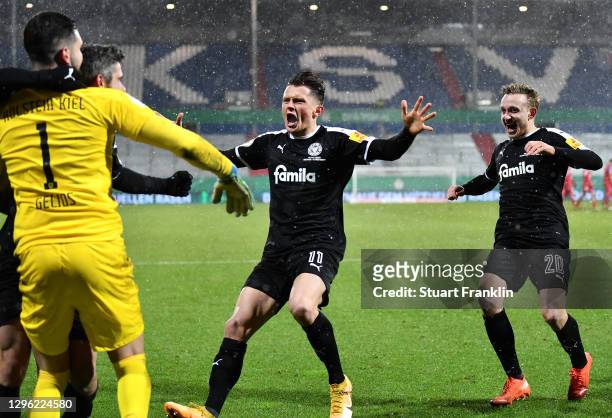 Fabian Reese and Jannik Dehm of Holstein Kiel run to celebrate with teammate Ioannis Gelios after winning the penalty shoot out during the DFB Cup...