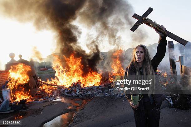 An activist holds up a crucifix as a barricade burns during evictions from Dale Farm travellers camp on October 19, 2011 near Basildon, England....