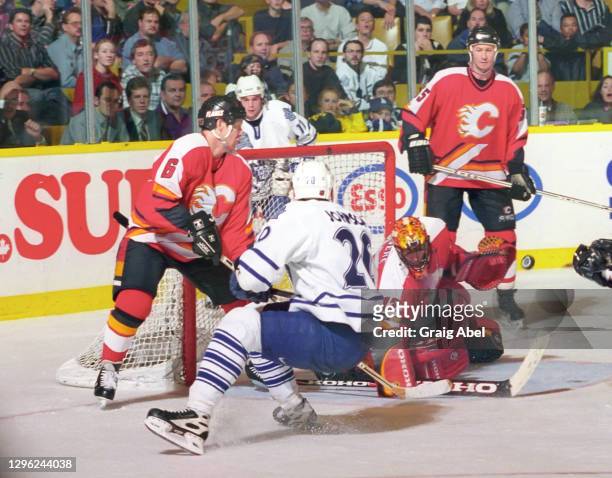 Jean-Sebastien Giguere, Phil Housley and Steve Smith of the Calgary Flames skate against Mike Johnson of the Toronto Maple Leafs during NHL game...
