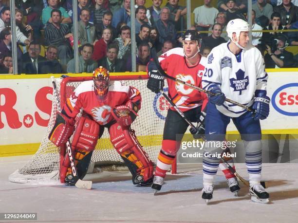 Jean-Sebastien Giguere and Todd Simpson of the Calgary Flames skate against Mike Johnson of the Toronto Maple Leafs during NHL game action on...