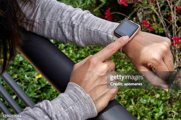 young woman tries out a generic but modern touch screen smart-watch on his wrist. - operating system stock pictures, royalty-free photos & images