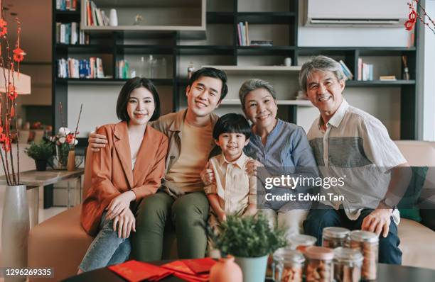 chinesische neue jahr mehrgenerationenfamilie sitzt auf sofa wohnzimmer blick auf die kamera lächelnd glücklich - chinese family stock-fotos und bilder