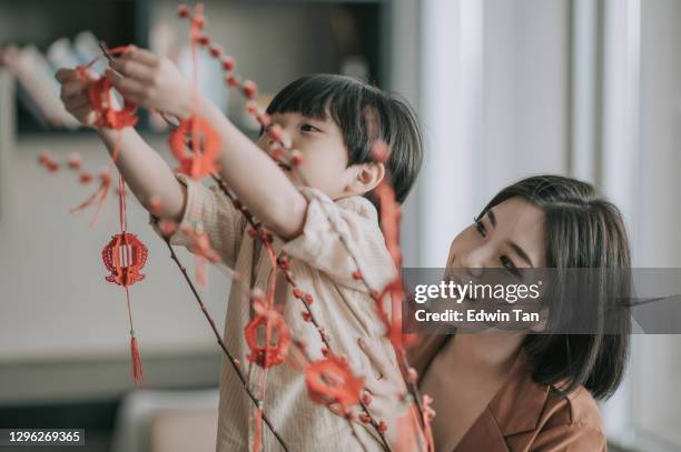 chinesische neujahr schöne frau mit ihrem sohn dekorieren haus wohnzimmer mit pussy weide und dekoration vorbereitung für familientreffen - chinese prepare for lunar new year stock-fotos und bilder