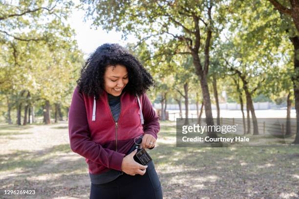 de jonge vrouw controleert insulinepomp en de monitor van de bloedsuiker terwijl het wandelen in openlucht - insulin pump stockfoto's en -beelden