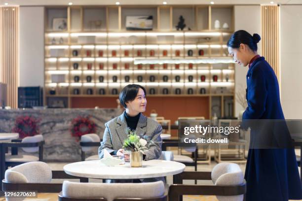 young waitress serving to business people - chinese restaurant stock pictures, royalty-free photos & images