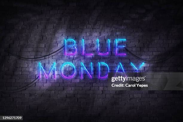 blue monday  text in neon style agains brick wall - blue monday stock-fotos und bilder