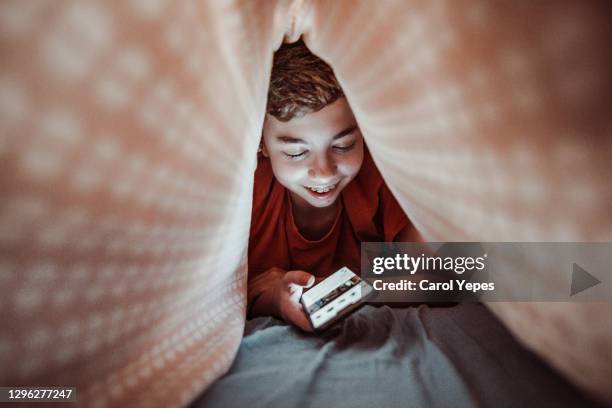 boy teenager in bed texting with smartphone at night - bedding stock pictures, royalty-free photos & images