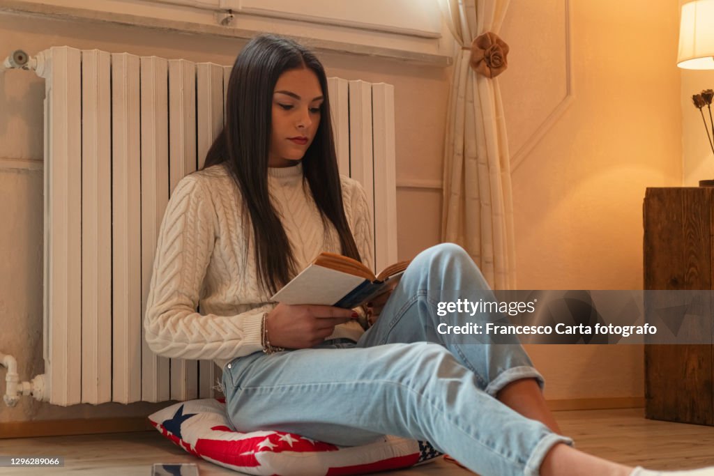 Woman reads a book sitting on the floor