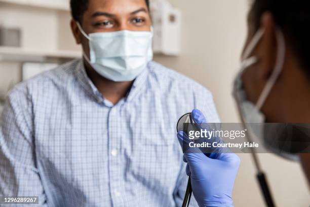 nurse or doctor uses stethoscope to listen to heart and lungs of patient who is wearing a protective face mask - black glove stock pictures, royalty-free photos & images