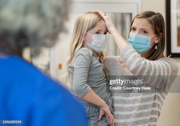 mother explains young daughter's fever and symptoms to a pediatrician at hospital - serviço de urgência imagens e fotografias de stock