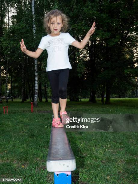 girl walking along a metal fence in a park, poland - playground balance beam stock pictures, royalty-free photos & images