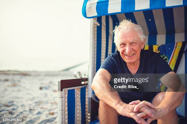 le vieux monsieur amical apprécie des vacances sur la mer baltique et s’asseyant dans une chaise de plage sur hiddensee/ allemagne - hiddensee photos et images de collection