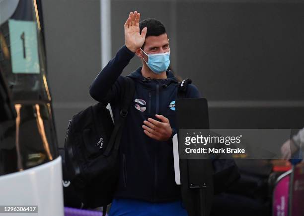 Novak Djokovic waves as he arrives at Adelaide Airport on January 14, 2021 in Adelaide, Australia. All players and staff arriving in Adelaide for the...