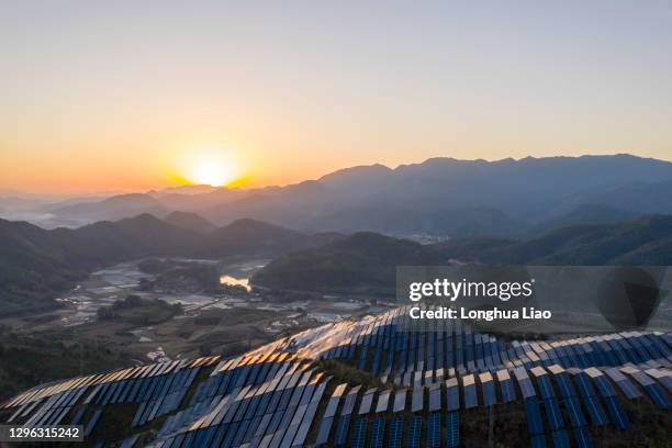 the setting sun shines on the solar panels on the mountain - panel fotografías e imágenes de stock