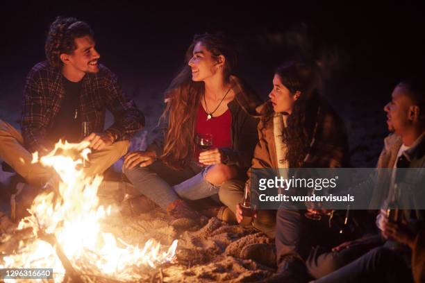晚上朋友在海灘篝火上喝酒瓶 - bonfire 個照片及圖片檔