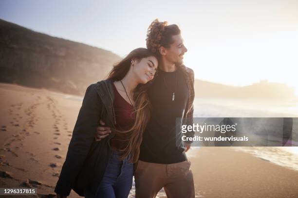 girlfriend walking head on shoulder of boyfriend on the beach - romantic couple walking winter beach stock pictures, royalty-free photos & images
