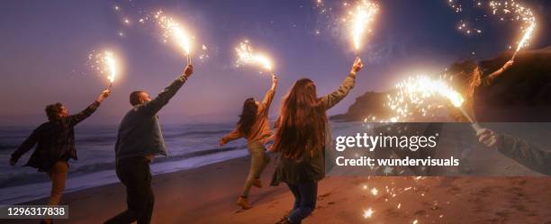 grupo de amigos corriendo con bengalas en la playa - chispas fotografías e imágenes de stock