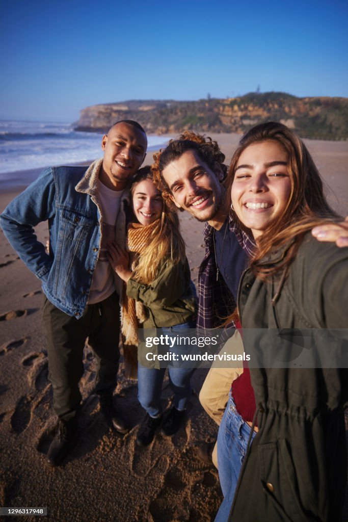 Friends group taking selfie at the beach during sunset