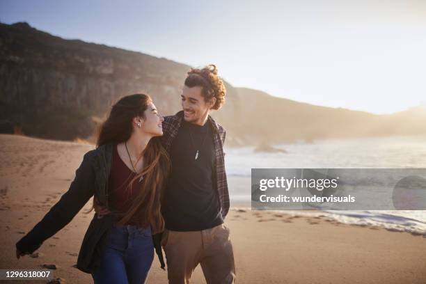 couple walking together on the beach during sunset - romantic couple walking winter beach stock pictures, royalty-free photos & images