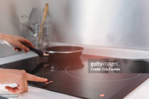 close up of woman using induction stove in kitchen - cooker fotografías e imágenes de stock