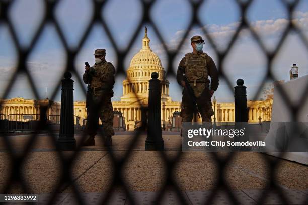 Members of the New York National Guard stand guard along the fence that surrounds the U.S. Capitol the day after the House of Representatives voted...