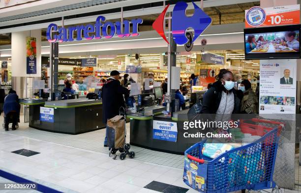 Customer wearing a protective face mask leaves a Carrefour supermarket on January 14, 2021 in Paris, France. The Canadian distributor Couche-Tard, a...