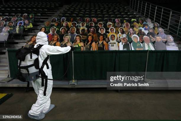 Cardboard cutouts of fans are seen as Alexander Espinoza of V&G Cleaning Services uses an electromagnetic sanitizer with hospital-grade disinfectant...