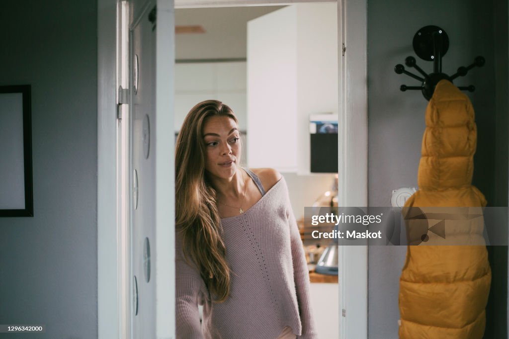 Playful woman looking through doorway at home