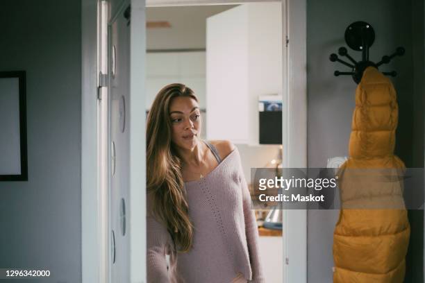playful woman looking through doorway at home - entering stock pictures, royalty-free photos & images