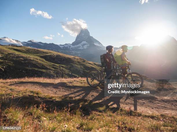 mountain bikers pause on dirt trail to contemplate landscape - valais canton stock pictures, royalty-free photos & images