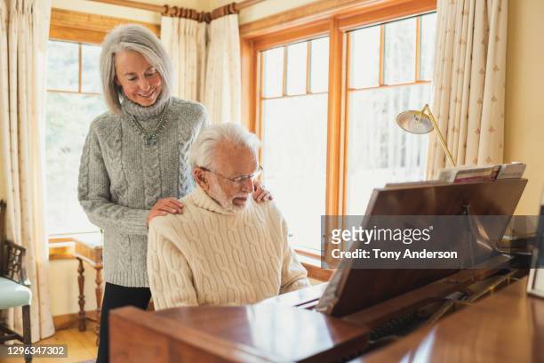 woman listening to man play piano - melody anderson stockfoto's en -beelden