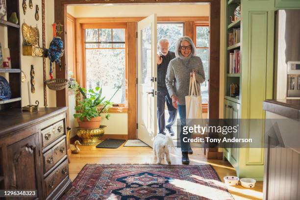 man and woman arriving home with shopping - man dog home stockfoto's en -beelden