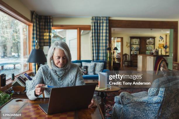 senior woman with thermometer and laptop at home - telemedicine choicepix stock pictures, royalty-free photos & images