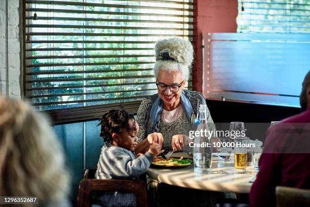 grandmother cutting child's food in restaurant - kid eating restaurant stock pictures, royalty-free photos & images