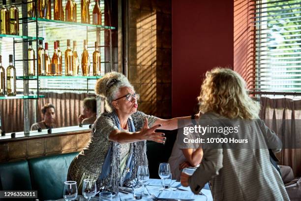 senior woman welcoming friend in restaurant - open arms hug stock pictures, royalty-free photos & images