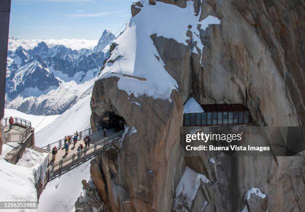 tourist on a bridge between rocks on the aiguille du midi - aiguille de midi fotografías e imágenes de stock