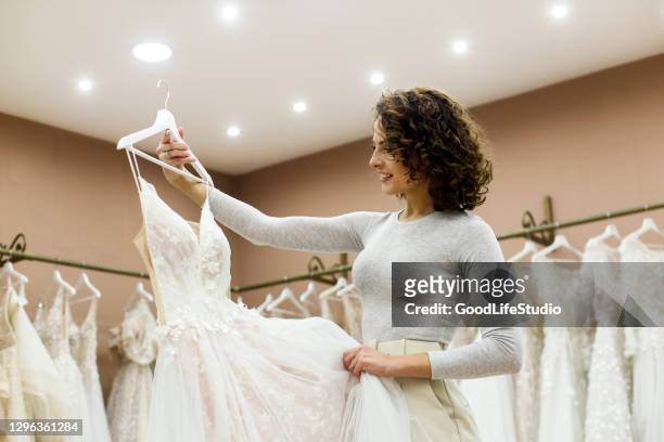 mujer joven mirando un vestido de novia en una tienda nupcial - wedding dress fotografías e imágenes de stock