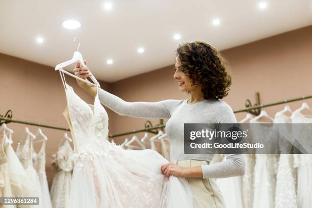 young woman looking at a wedding dress in a bridal shop - brudklänning bildbanksfoton och bilder