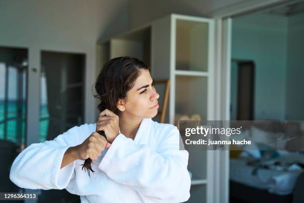 positive woman in bathrobe squeezing wet hair - nasses haar stock-fotos und bilder