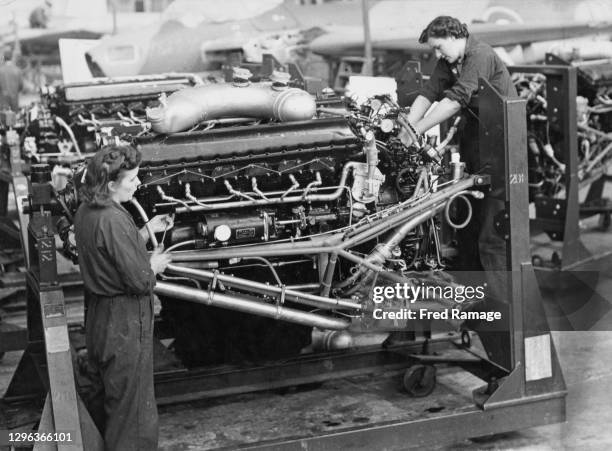 Two women engineers at work installing one of the two 1,710 hp Rolls-Royce Merlin 76/77 V12 piston aero engines that power the De Havilland DH98...