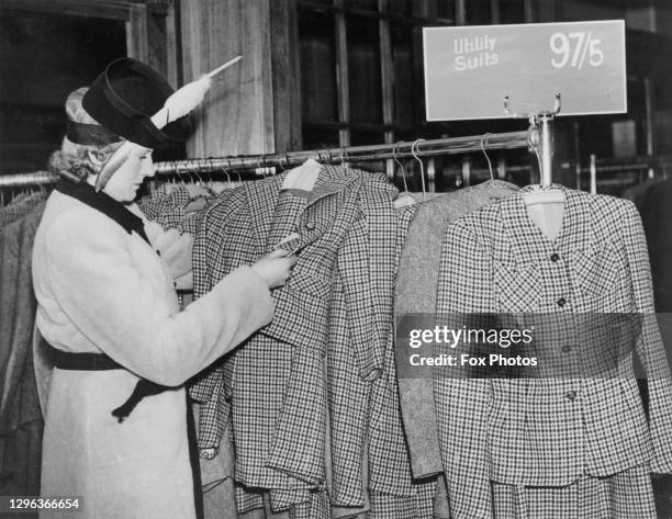 Customer examines a clothes rack collection of women's utility wear suits in a clothing store as shortage of clothing materials and labour due to...