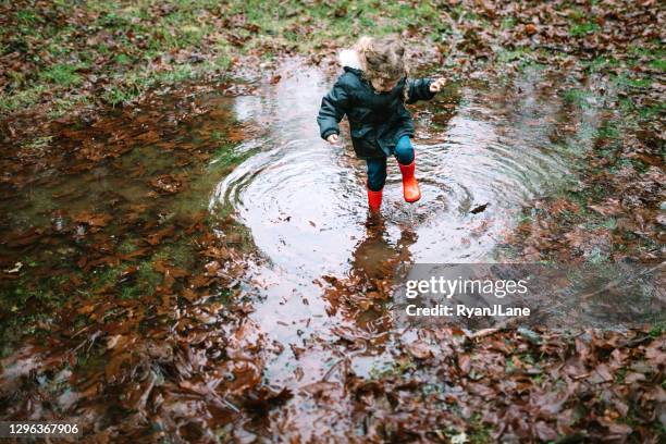 little girl plays in puddles from heavy rainfall - stamping feet stock pictures, royalty-free photos & images