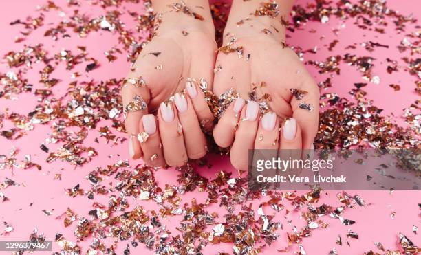 stylish pastel pink beige nails holding many multicolored sparkles - manicure foto e immagini stock
