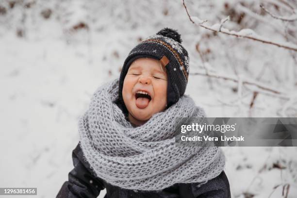 cute little boy catching snowflakes with her tongue in beautiful winter park - portrait winter stock pictures, royalty-free photos & images