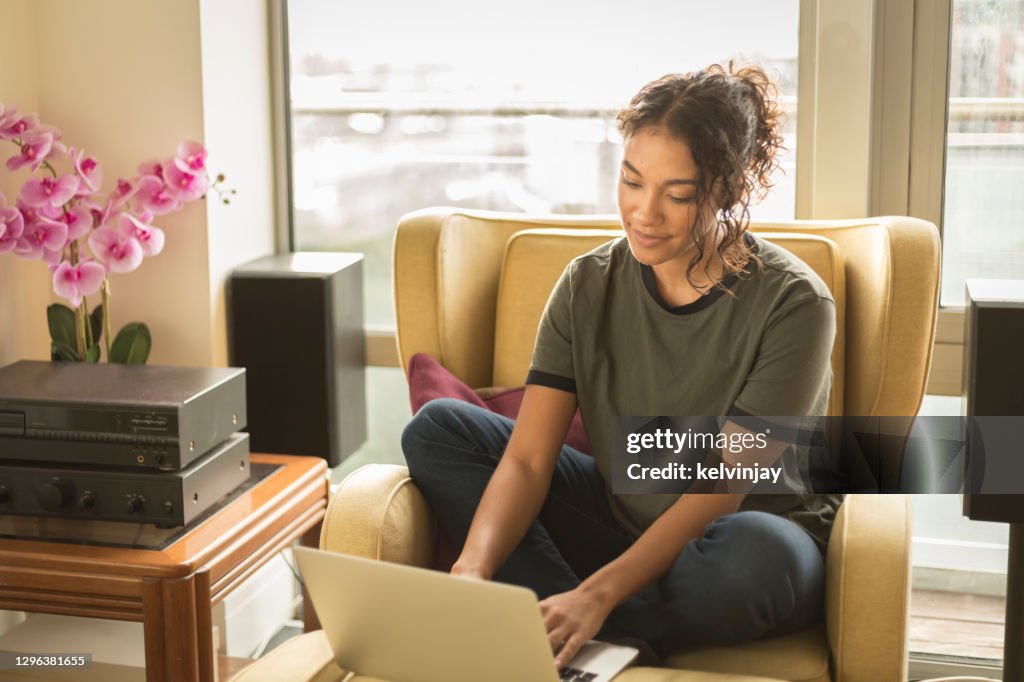 Glad ung kvinna hemma med hjälp av en bärbar dator