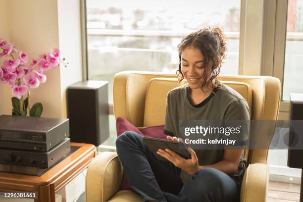 happy young woman at home using a digital tablet - stereo stock pictures, royalty-free photos & images