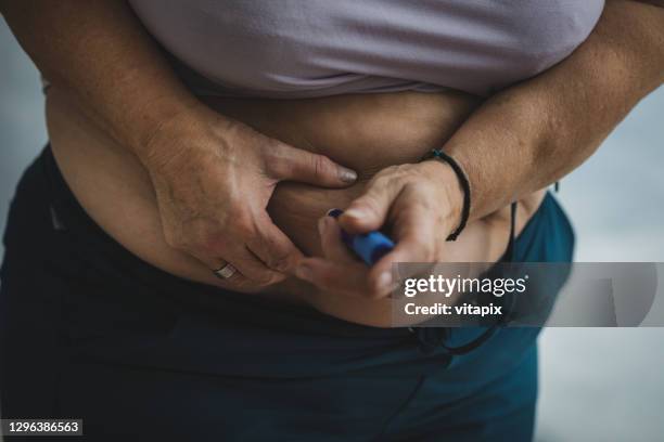 diabetic woman receiving an insulin shot - injecting stomach stock pictures, royalty-free photos & images