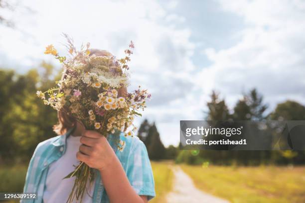 child hidden behind a bouquet of wildflowers - bunch imagens e fotografias de stock