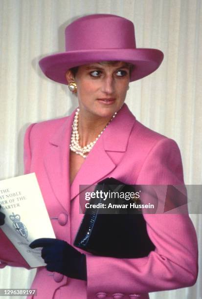 Diana, Princess of Wales, wearing a pink wool suit designed by Catherine Walker with a matching hat designed by Philip Sommerville and navy blue...